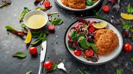Breaded Chicken Kiev breast stuffed with butter, garlic and herbs served with vegetables in a plate.