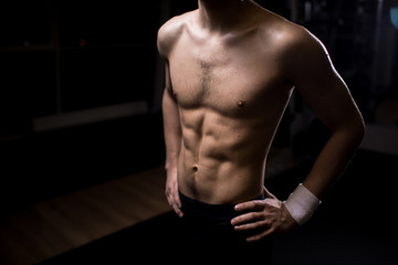 Fototapeta na wymiar Wet torso of muscular young man in akimbo pose having short break between exercises