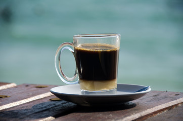 Close up Coffee cup on wood table and view of tropical beach.