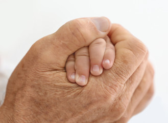 Senior man holding his little grandchild's hand on white background, closeup