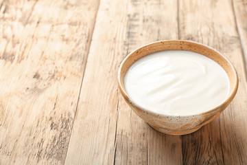Tasty yogurt in dish on wooden table