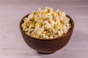 Ceramic bowl with popcorn on wooden table
