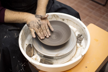 Artist makes clay pottery on a spin wheel