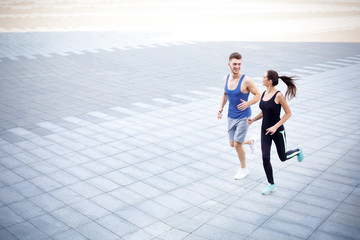 Young woman and man running in city copy space