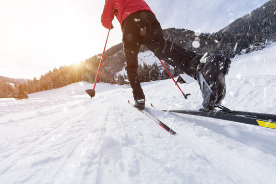 Man cross-country skiing during sunny winter day.