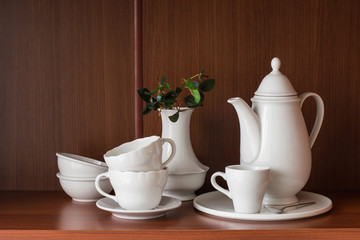     White porcelain tableware for coffee, located on a shelf in the closet.