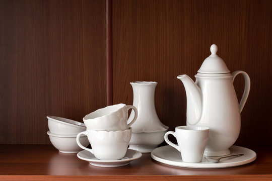     White porcelain tableware for coffee, located on a shelf in the closet.