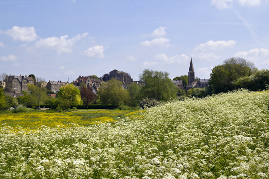 View Across Fields To Historic Malmesbury Abbey And The Town In Spring Sunshine In The Cotswolds,Wiltshire, UK