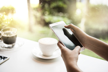 Hand using smart phone searching needed information for work in internet via cell telephones in a coffee shop