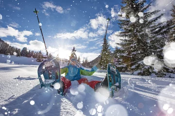 Photo sur Aluminium Sports dhiver Heureux marcheur en raquettes dans la neige poudreuse avec de beaux rayons de soleil.