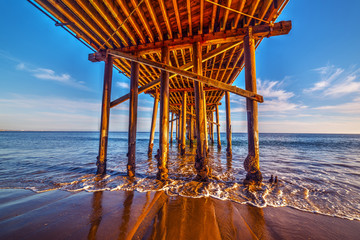Wooden poles under Malibu pier - obrazy, fototapety, plakaty