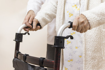 Pielęgniarz pomaga iść starej kobiecie trzymającej się chodzika. - obrazy, fototapety, plakaty