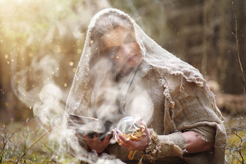 A man in a cassock spends a ritual in a dark forest