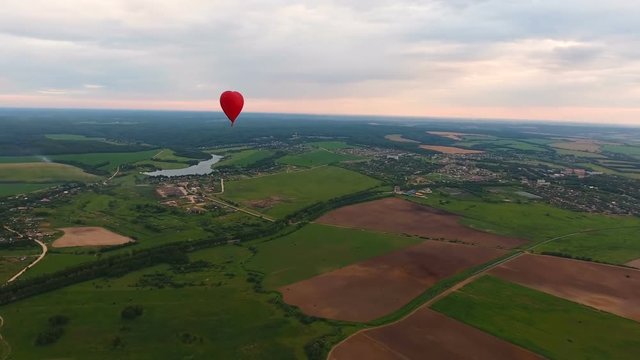 Red balloon in the shape of a heart.Aerial view:Hot air balloon in the sky over a field in the countryside in the beautiful sky and sunset.
