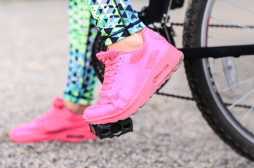 a young girl goes in for sports in the fresh air . Sports clothing pink color , sitting on the bike