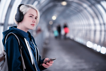 Young student listening to music in big headphones in the subway