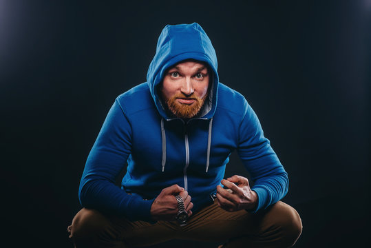 young bearded male bully sits with a spiteful face on a black background
