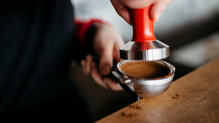 Barista is preparing making coffee with temper in hands