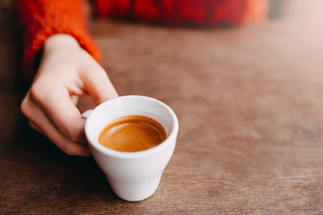 Woman is holding in hand hot coffee espresso in white small glass cup