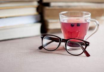 Blueberry tea in glass cap with   eyeglasses  on the background of books