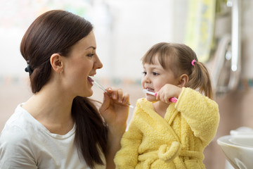 mother teaching daughter child teeth brushing in bathroom