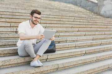 Smiling businessman working with tablet outdoors