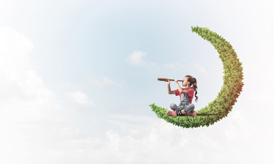 Concept of careless happy childhood with girl on green moon