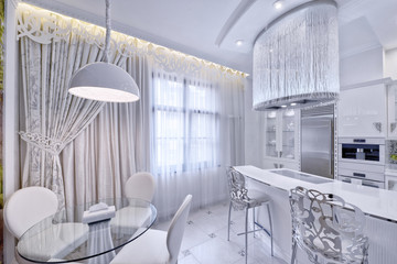 Modern design interior with white glossy kitchen in a luxurious apartment in gray and white tones.