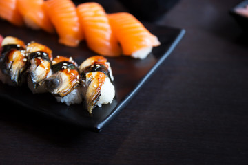 eel and salmal sushi sashimi on black dish with empty table