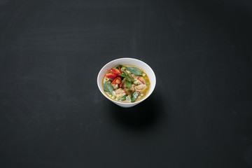 Thai style spicy green curry with pork in a bowls on black background.