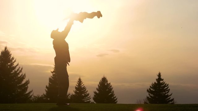 Father having fun with daughter silhouette. Father lifting up his daughter in the park while sunset.