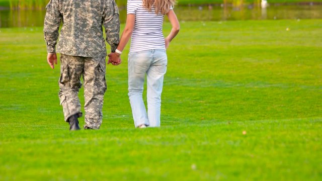 Army soldier reunited with wife, close up. Caucasian military man with girlfriend, back view.