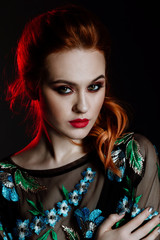 Fototapeta premium Studio portrait of the beautiful red-haired girl of model with a bright make-up on a gray background. Red lips and smoky eyes make up. glamour lady. Haircare, skincare concept