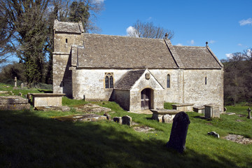 Fototapeta na wymiar Spring sunshine on the picturesque old church at Duntisbourne Rouse in the Cotswolds, Gloucestershire, UK