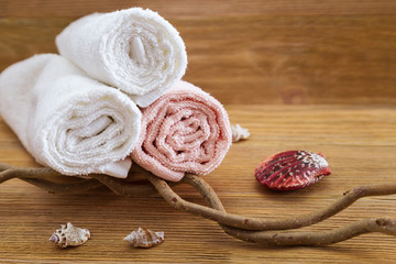 Rolled bath towels pink and white colored on wooden table at hotel spa