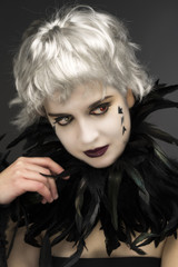 Androgynous witch girl with red-green eyes and black feathers