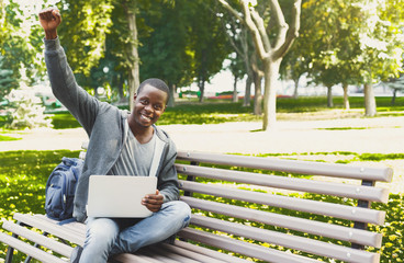Fototapeta premium Happy successful african-american student with arm raised in the air