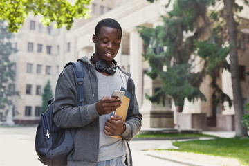 Happy african-american student texting in university campus