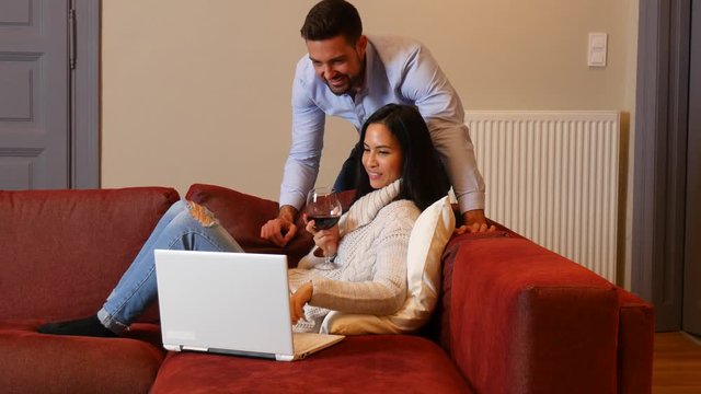A young couple using a laptop together in the living room.
