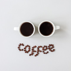 Coffee word made of coffee beans and two cups of coffee, top view