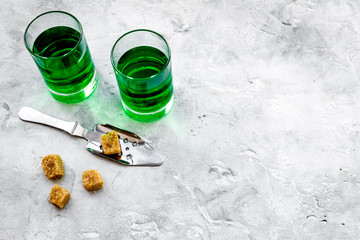 Traditions of drinking absinthe. Special spoon and sugar cubes near shots on grey background top view copy space