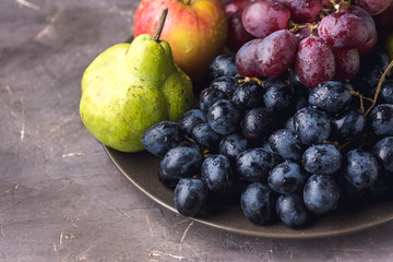 Naklejka na ściany i meble Beautiful Ripe Fruits on Plate Apple Pears and Grapes Dark Photo Dark Background Autumn Seasonal Fruits Above