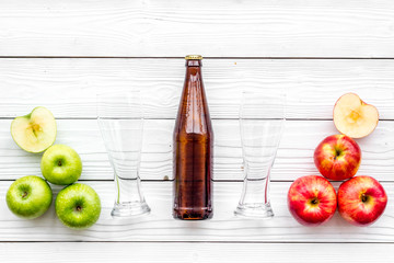 Apple cider. Low-alcoholic beveradge in dark bottle near beer glasses and fresh apples on white wooden background top view copy space