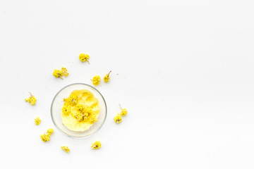 Aromatic spa salt. Yellow spa salt with delicate spring flowers on white background top view copy space