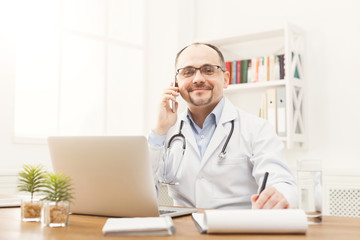 Happy doctor talking on the phone with his patient