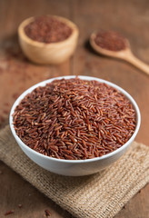 Rice berry in white bowl on wood background