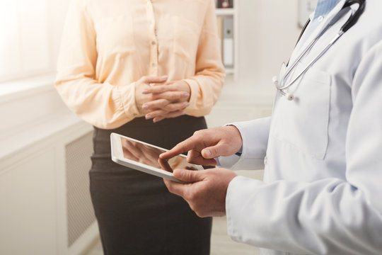 Closeup of a doctor pointing into tablet and patient