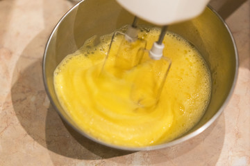 Beat egg with a white mixer in an iron bowl