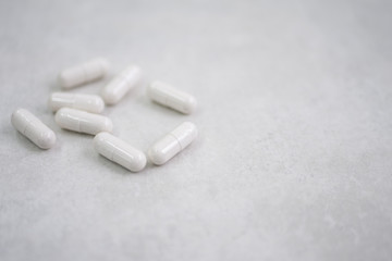 Fototapeta na wymiar many white pills on grey white background, in left side