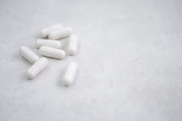 many white pills on grey white background, in left side